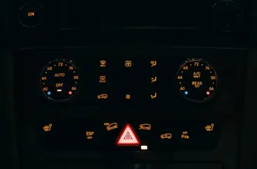 Dashboard controls of a vehicle illuminated at night.